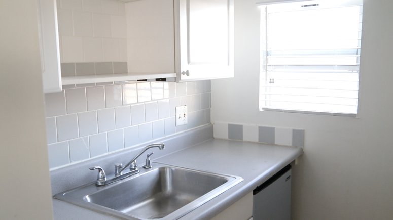 A kitchen sink with white tiles Description automatically generated
