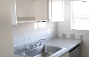 A kitchen sink with white tiles Description automatically generated