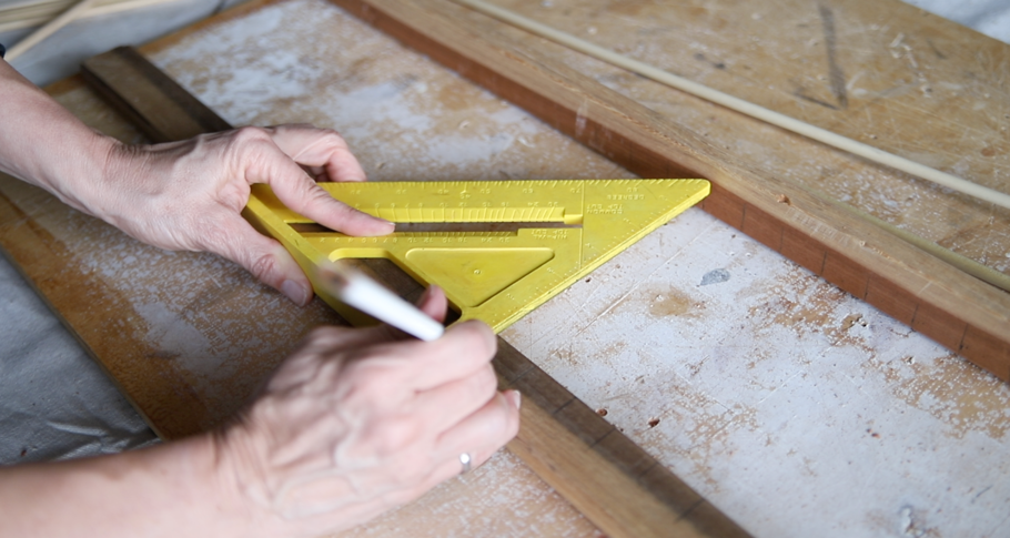 A person using a ruler to measure a piece of wood Description automatically generated