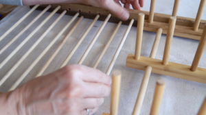 A person's hands working on a loom Description automatically generated